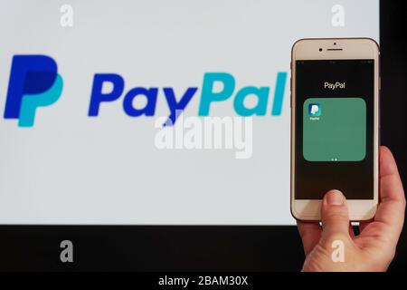 PayPal Holdings Inc. Online trasferimenti di denaro e pagamenti concetto bancario con logo. La mano tiene il telefono cellulare prima dello schermo con l'icona dell'applicazione PayPal. Foto Stock