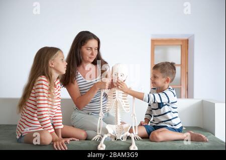 lezione di casa di famiglia di anatomia bella madre che spiega la struttura umana ai bambini sceleton Foto Stock