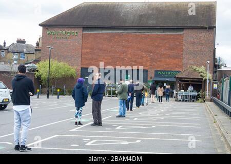 Londra, Regno Unito. 28 marzo 2020. I clienti fanno la fila nel parcheggio in attesa di entrare in un supermercato Waitrose & Partners a Northwood, a nord-ovest di Londra. La catena di supermercati ha implementato un sistema di accesso controllato nei suoi negozi che mantiene i clienti a 2 metri di distanza, limita le scorte e garantisce che le scorte sugli scaffali rimangano disponibili per tutti i clienti. Il Dipartimento della Salute ha annunciato che finora nel Regno Unito sono morte 1,019 persone a causa del coronavirus, con 17,089 casi confermati e 103,687 persone con test negativi per il virus. Credit: Stephen Chung / Alamy Live News Foto Stock