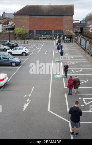 Londra, Regno Unito. 28 marzo 2020. I clienti fanno la fila nel parcheggio in attesa di entrare in un supermercato Waitrose & Partners a Northwood, a nord-ovest di Londra. La catena di supermercati ha implementato un sistema di accesso controllato nei suoi negozi che mantiene i clienti a 2 metri di distanza, limita le scorte e garantisce che le scorte sugli scaffali rimangano disponibili per tutti i clienti. Il Dipartimento della Salute ha annunciato che finora nel Regno Unito sono morte 1,019 persone a causa del coronavirus, con 17,089 casi confermati e 103,687 persone con test negativi per il virus. Credit: Stephen Chung / Alamy Live News Foto Stock