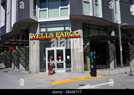 Un uomo cammina attraverso un ramo della Wells Fargo Bank nel distretto di Soma di San Francisco, California, domenica 9 febbraio 2020. Foto Stock