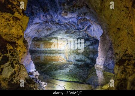 Una grotta con pareti colorate e un serbatoio pieno d'acqua. Foto Stock