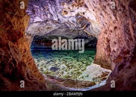 Una grotta con pareti colorate e un serbatoio pieno d'acqua. Foto Stock