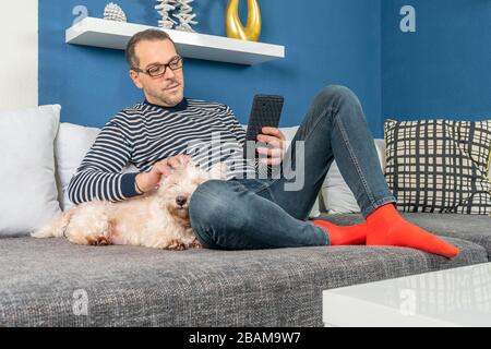 un uomo si rilassa sul divano con il suo cane Foto Stock