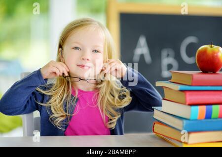 Scolari intelligenti che studiano con un mucchio di libri sulla sua scrivania. Ragazza giovane che fa il suo lavoro. Istruzione e apprendimento a distanza per i bambini. Pelliccia di homeschooling Foto Stock