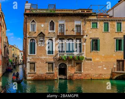 Venezia, Italia - 25 settembre 2017: Gondole con turisti che passano accanto alle pittoresche facciate e ai ponti dell'edificio in uno dei canali Foto Stock