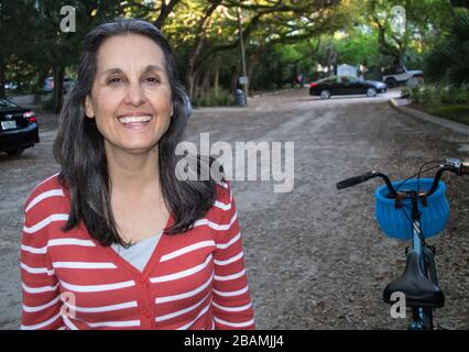 La donna sorridente si riposa dal suo giro in bicicletta Foto Stock