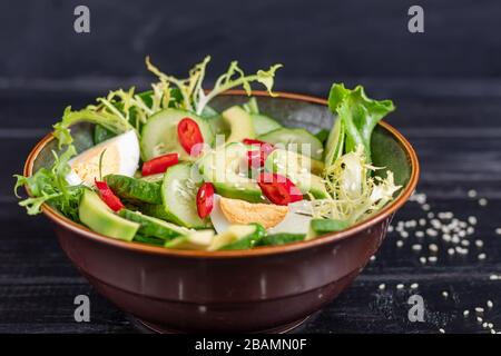 Insalata di cetrioli freschi, foglie di spinaci, rucola, avocado. Servito con fette di uova e pepe rosso. Alimentazione dietetica. Colazione per tutta la famiglia Foto Stock