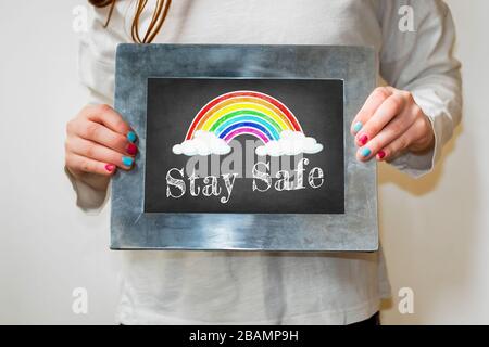 Disegno in lavagna con arcobaleno e le parole rimangono al sicuro Foto Stock