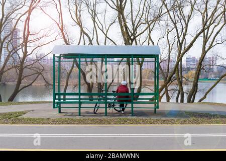 Donna caucasica con una bicicletta si trova in un parco e guarda il fiume Foto Stock