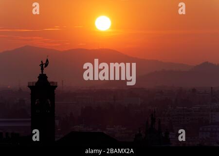 Statua in cima al campanile della Chiesa di Sant'Alessandro della Croce raffigurata contro l'alba, Bergamo, Italia Foto Stock