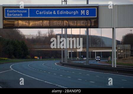 Glasgow, Regno Unito. 28 Marzo 2020. Nella foto: Segnali stradali lungo le autostrade M8 e M80 che leggono: "STAY HOME SAVE LIVES" il Coronavirus Pandemic ha costretto il governo britannico a chiudere tutte le principali città del Regno Unito e a far sì che le persone rimano a casa, che ha lasciato le autostrade e tutte le altre strade libere dal solito traffico naso a coda che altrimenti sarebbe lì. Credit: Colin Fisher/Alamy Live News Foto Stock