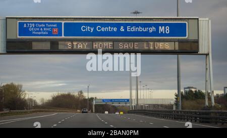 Glasgow, Regno Unito. 28 Marzo 2020. Nella foto: Segnali stradali lungo le autostrade M8 e M80 che leggono: "STAY HOME SAVE LIVES" il Coronavirus Pandemic ha costretto il governo britannico a chiudere tutte le principali città del Regno Unito e a far sì che le persone rimano a casa, che ha lasciato le autostrade e tutte le altre strade libere dal solito traffico naso a coda che altrimenti sarebbe lì. Credit: Colin Fisher/Alamy Live News Foto Stock