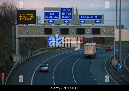 Glasgow, Regno Unito. 28 Marzo 2020. Nella foto: Segnaletica stradale lungo le autostrade M8 e M80 che recita: "STAY HOME PROTECT NHS SAVE LIVES" il Coronavirus Pandemic ha costretto il governo britannico a chiudere tutte le principali città del Regno Unito e a far sì che le persone restino a casa, che ha lasciato le autostrade e tutte le altre strade libere dal solito traffico naso a coda che altrimenti sarebbe lì. Credit: Colin Fisher/Alamy Live News Foto Stock