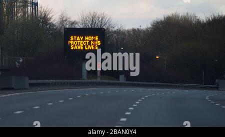 Glasgow, Regno Unito. 28 Marzo 2020. Nella foto: Segnaletica stradale lungo le autostrade M8 e M80 che recita: "STAY HOME PROTECT NHS SAVE LIVES" il Coronavirus Pandemic ha costretto il governo britannico a chiudere tutte le principali città del Regno Unito e a far sì che le persone restino a casa, che ha lasciato le autostrade e tutte le altre strade libere dal solito traffico naso a coda che altrimenti sarebbe lì. Credit: Colin Fisher/Alamy Live News Foto Stock