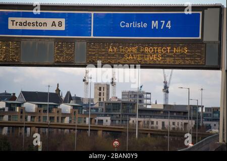 Glasgow, Regno Unito. 28 Marzo 2020. Nella foto: Segnaletica stradale lungo le autostrade M8 e M80 che recita: "STAY HOME PROTECT NHS SAVE LIVES" il Coronavirus Pandemic ha costretto il governo britannico a chiudere tutte le principali città del Regno Unito e a far sì che le persone restino a casa, che ha lasciato le autostrade e tutte le altre strade libere dal solito traffico naso a coda che altrimenti sarebbe lì. Credit: Colin Fisher/Alamy Live News Foto Stock