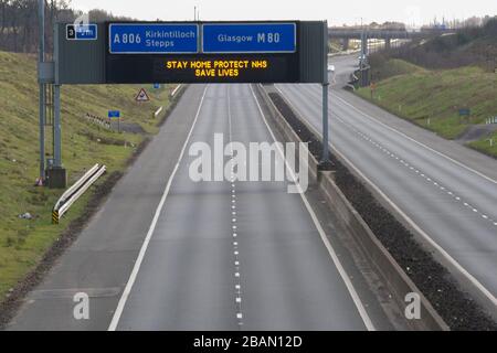 Glasgow, Regno Unito. 28 Marzo 2020. Nella foto: Segnaletica stradale lungo le autostrade M8 e M80 che recita: "STAY HOME PROTECT NHS SAVE LIVES" il Coronavirus Pandemic ha costretto il governo britannico a chiudere tutte le principali città del Regno Unito e a far sì che le persone restino a casa, che ha lasciato le autostrade e tutte le altre strade libere dal solito traffico naso a coda che altrimenti sarebbe lì. Credit: Colin Fisher/Alamy Live News Foto Stock