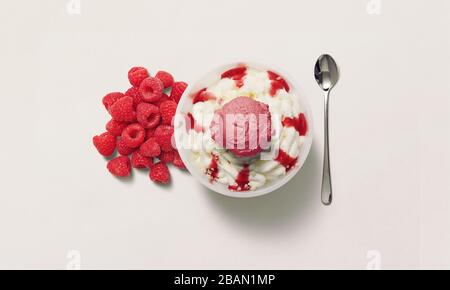 Gelato in un recipiente bianco con un mucchio di lamponi sul lato. Lamponi, gelato, cucchiaio, vista dall'alto. Foto Stock