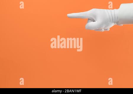 Punta la mano nel guanto bianco su sfondo arancione con spazio per la copia Foto Stock