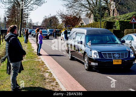 I residenti locali pagano il rispetto come il cuore che trasporta il cadavere della vittima del coronavirus guida attraverso il villaggio vicino a Uden durante una processione funeraria.solo un massimo di 30 persone possono visitare un funerale o cremazione, questo è riportato dal BGNU, l'associazione di settore del settore funerale. Sarà discusso con il prossimo di parenti che saranno invitati. Per evitare che il virus si diffonda, caffè e tè non sono più serviti. Foto Stock