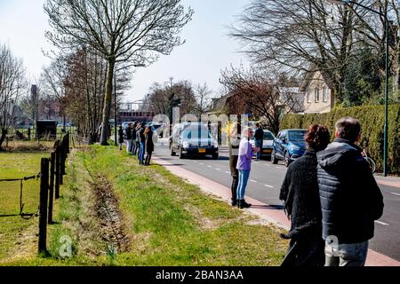 I residenti locali pagano il rispetto come il cuore che trasporta il cadavere della vittima del coronavirus guida attraverso il villaggio vicino a Uden durante una processione funeraria.solo un massimo di 30 persone possono visitare un funerale o cremazione, questo è riportato dal BGNU, l'associazione di settore del settore funerale. Sarà discusso con il prossimo di parenti che saranno invitati. Per evitare che il virus si diffonda, caffè e tè non sono più serviti. Foto Stock