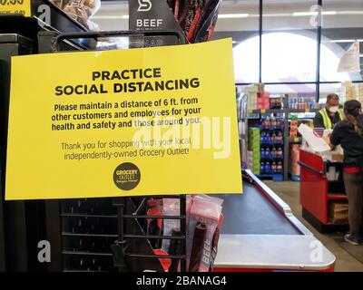 L'accesso al negozio di alimentari consiglia agli acquirenti di "praticare il social distancing" e "mantenere una distanza di 6 metri da altri clienti e dipendenti" visto al mercato Grocery Outlet di El Cerrito, nella California Bay Area. Marzo 2020. Foto Stock