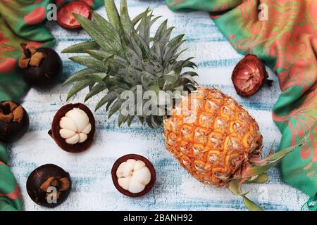 Ananas e mangostene su sfondo blu, vista dall'alto, orientamento orizzontale Foto Stock