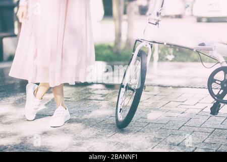 Giovane donna si trova accanto a una bicicletta bianca nel parco Foto Stock