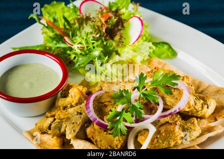 Delizioso kebab di pollo disossato su spiedino servito su pane pita arabo Foto Stock