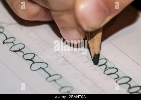 Primo piano del capretto della scuola primaria che fa il lavoro sul libro di excercise di scrittura della lettera Foto Stock