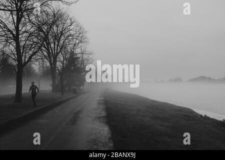 Le temperature calde primaverili creano una fitta nebbia su un lago ghiacciato di Dow a Ottawa. La nebbia si riversa sulle rive per creare un effetto localizzato inusuale. Foto Stock