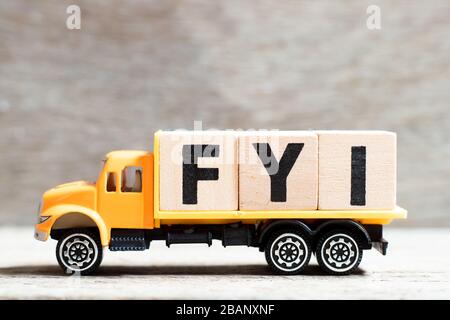 Blocco di lettere di tenuta del camion in parola FYI (abbreviazione di per le vostre informazioni) su sfondo di legno Foto Stock