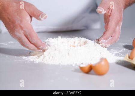 Mani maschili che lavorano con farina e uova Foto Stock