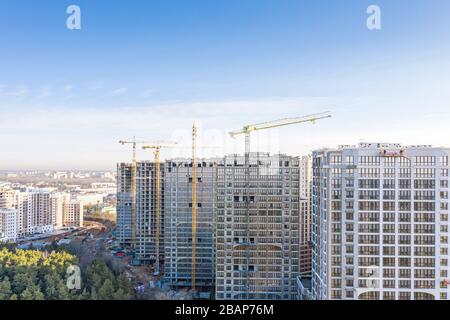 veduta aerea panoramica di un grande cantiere civile in corso con gru gialle contro il cielo blu Foto Stock