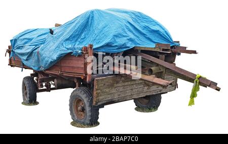 Vecchio carrello per rimorchio per trattori rurali rosso con tronchi di legno e copertura in plastica per teloni blu isolata su bianco Foto Stock