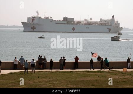 Norfolk, Stati Uniti. 28 Marzo 2020. La gente si riunisce per guardare la nave militare del comando di Sealift USNS Comfort (T-AH 20) parte dalla stazione navale Norfolk, Va., 28 marzo 2020. Il comfort si sta sviluppando a sostegno degli sforzi di risposta del nationÕs COVID-19 e fungerà da ospedale di riferimento per pazienti non COVID-19 attualmente ammessi in ospedali a terra. In questo modo gli ospedali con sede a terra possono concentrare i propri sforzi sui casi COVID-19. Una delle missioni del Dipartimento di DefenseÕs è il sostegno alla difesa delle autorità civili. Credit: Storms Media Group/Alamy Live News Foto Stock