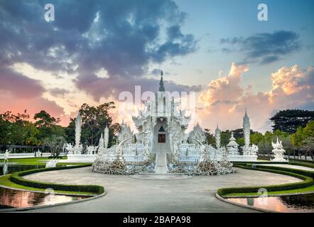 Wat Rong Khun il tempio bianco e uno stagno al tramonto spettacolare sfondo in Chiang Rai, Thailandia Foto Stock