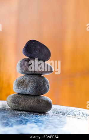 Quattro Pebble Stones impilati su una superficie luminosa con sfondo scuro Foto Stock