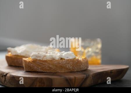 Fette di ciabatta con marmellata d'arancia e ricotta su tavola d'oliva Foto Stock