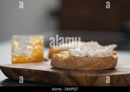 Fette di ciabatta con marmellata d'arancia e ricotta su tavola d'oliva Foto Stock