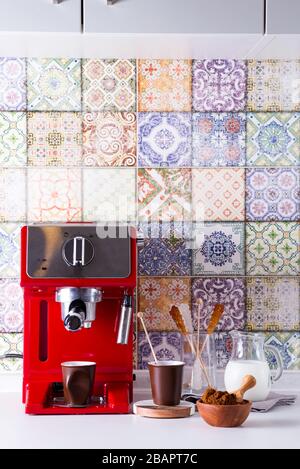 Macchina da caffè in casa su piano cottura con due tazze, latte e zucchero su bastoni. Caffè a casa. Foto Stock