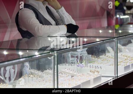 Ragazza vicino a un venditore di banco in un negozio di gioielli. Vendita Foto Stock