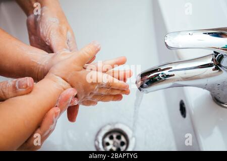 Madre e figlio lavano le mani con acqua e sapone nel bagno di casa. Pulizia dell'igiene delle mani per prevenire l'insorgenza di coronavirus. Protezione agai Foto Stock