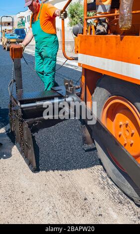 Operai edili nel corso di asfaltatura lavori stradali indossando tute. Il lavoro manuale sul sito in costruzione. Foto Stock