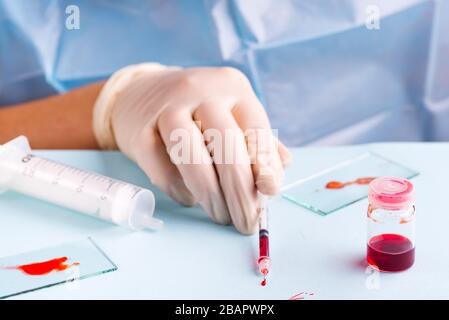 Analisi del sangue. Primo piano di una siringa per lo scienziato femminile che tiene la siringa mentre lavora in laboratorio Foto Stock
