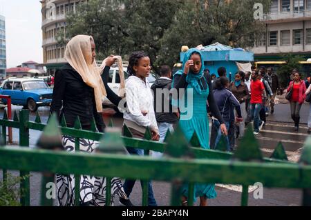 Donna che cammina in un incrocio trafficato nel centro della città di Addis Abeba, Etiopia Foto Stock