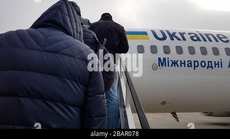 Ucraina, Borispol - 27 marzo 2020: Turisti non identificati si arrampicano su un aereo. I passeggeri viaggiano in fila sull'aereo. Ukraine International Airlines Foto Stock