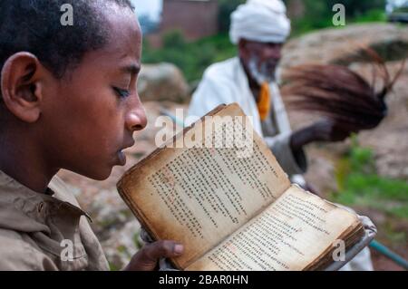 Lalibela, Amhara Region, Etiopia. Un bambino prega in una delle chiese di Lalibela. Nel XII secolo, il Principe Lalibela costruito una dozzina di chiese excav Foto Stock