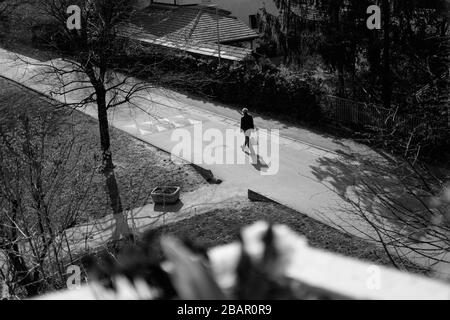 Kranj, Slovenia, 21 marzo 2020: Un uomo di ritorno dal negozio di alimentari cammina lungo una strada vuota durante l'epidemia di coronavirus a livello nazionale. Foto Stock