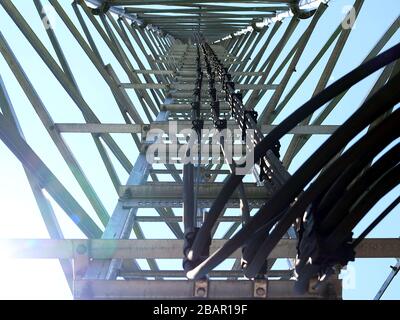 La fotografia offre una prospettiva verso l'alto della struttura interna di una torre di telecomunicazioni. L'immagine rivela la complessa struttura in acciaio che c Foto Stock